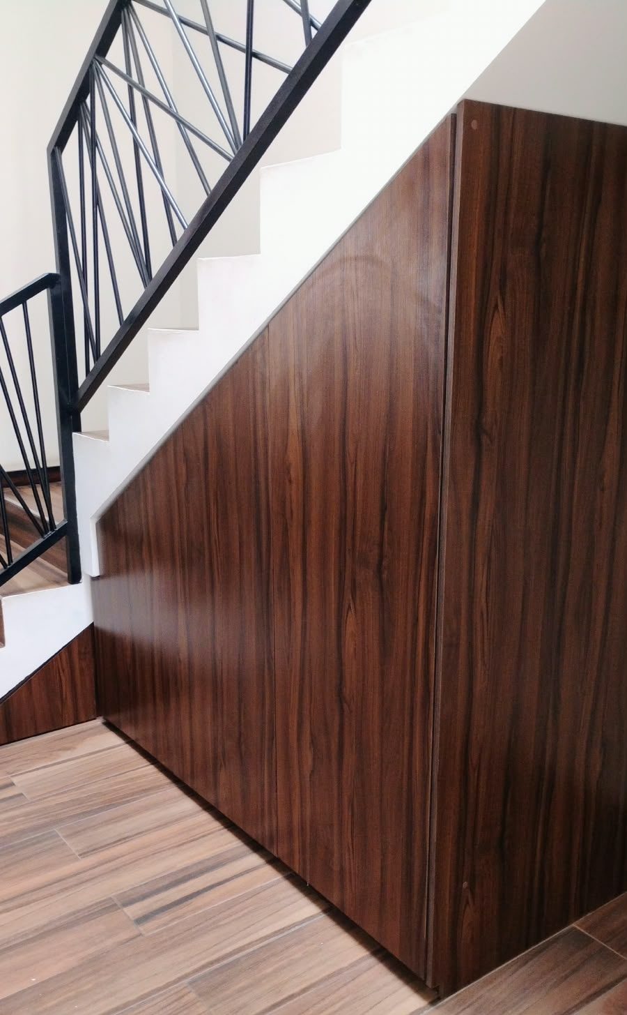 Clóset de madera oscura integrado bajo la escalera de una casa