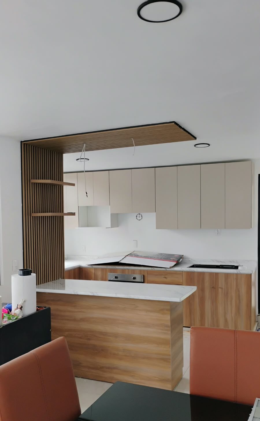 Cocina integral con isla de madera, alacenas claras y plafón de lamas