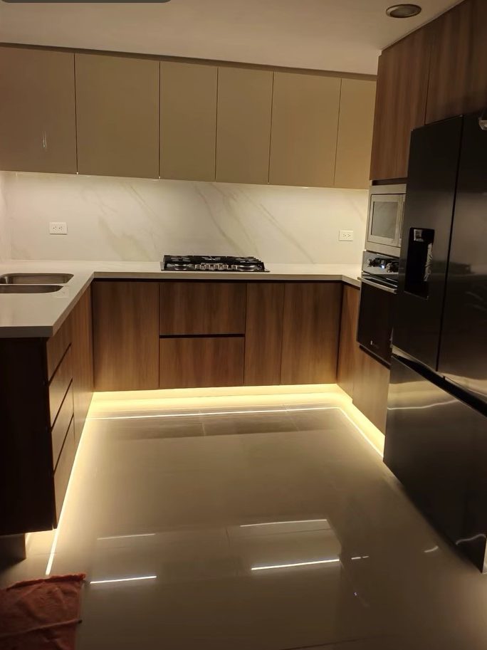 Cocina integral en U con frentes de madera e iluminación LED en el zócalo