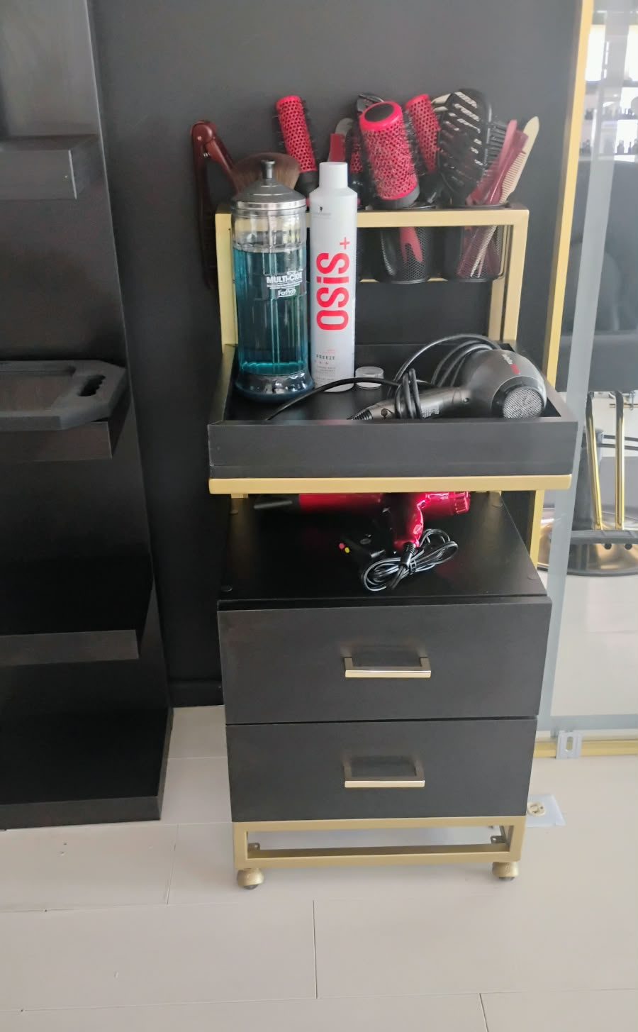 Mueble auxiliar para salón de belleza en negro y dorado con cajones y repisa