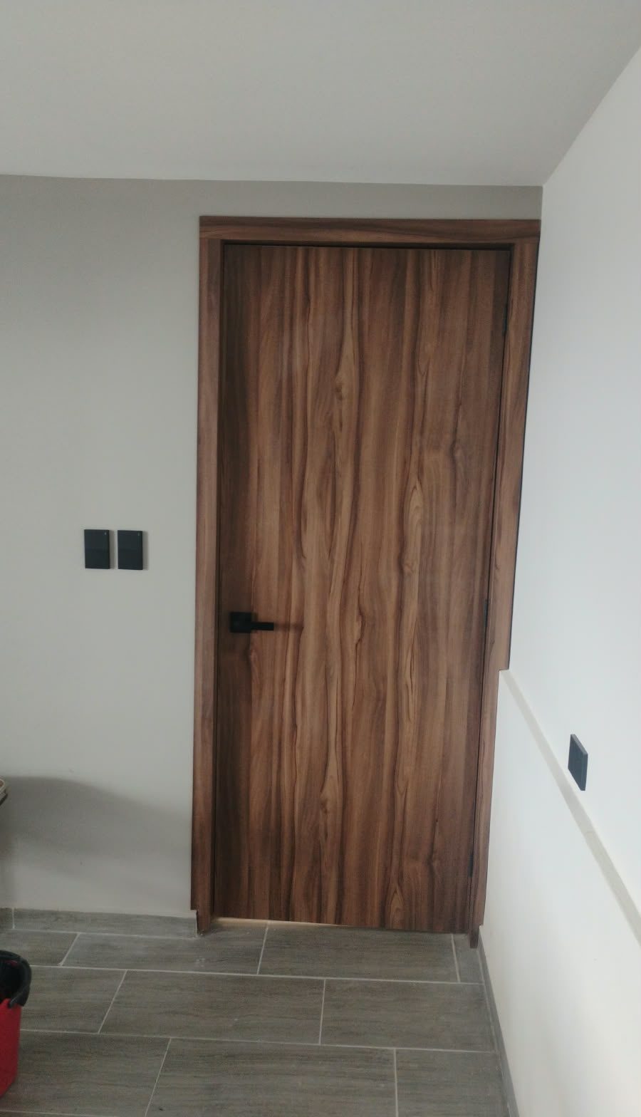 Puerta de madera con veta continua y herraje negro instalada a medida