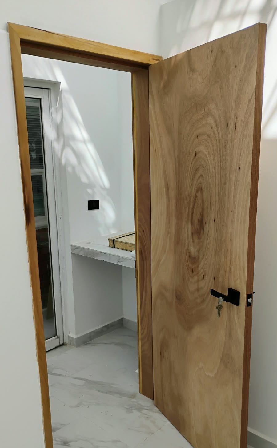 Puerta de madera natural abierta con marco a juego