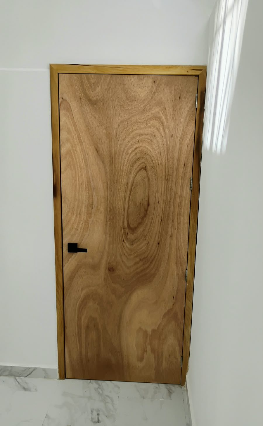 Puerta de madera natural con veta marcada instalada en un cuarto luminoso