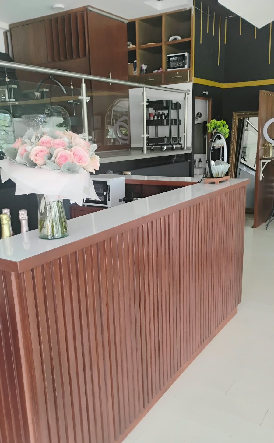 Mostrador de recepción comercial con frente de lamas de madera y cubierta clara